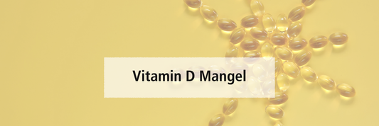 Vitamin-D-Kapseln in Form einer Sonne im Hintergrund, vorne der Schriftzug ‚Vitamin-D-Mangel‘.
